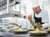 Happy chef garnishing appetizer plates at order station