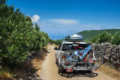 Car with roofbox and bicycle on the road in an olive grove, Hvar, Croatia