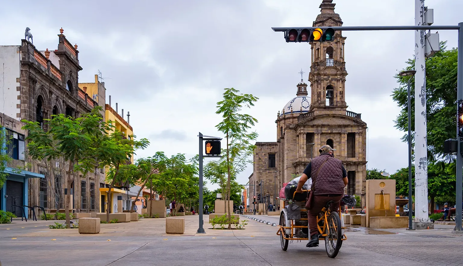 El ciclista está manejando su bicicleta por la avenida Alcalde