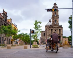 El ciclista está manejando su bicicleta por la avenida Alcalde