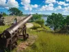 Old cannon in the fort is looking at sea with amazing clouds and island on background