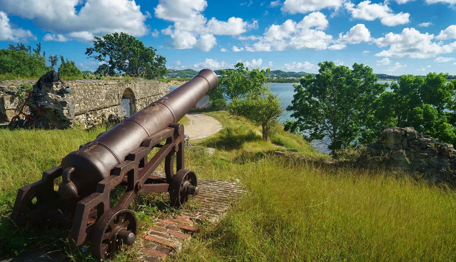 Old cannon in the fort is looking at sea with amazing clouds and island on background