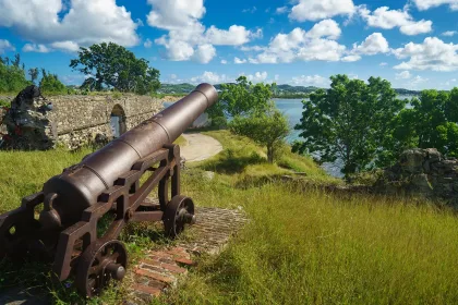 Old cannon in the fort is looking at sea with amazing clouds and island on background