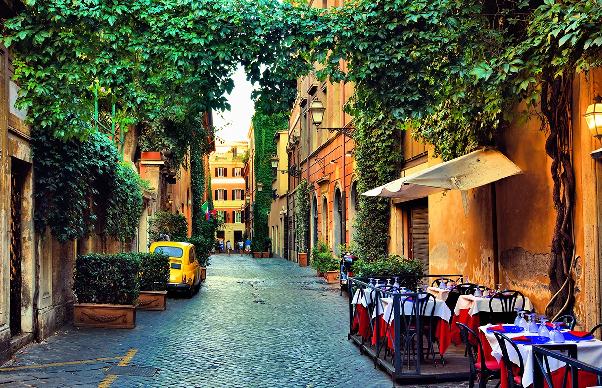 Beautiful ancient street in Rome lined with leafy vines and cafe
