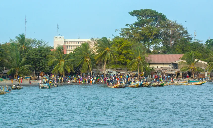 African people and boats on the shoreline of Banjul in Gambia, West Africa
