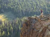 A woman hiking on a rocky ledge in Cathedral Provincial Park; lake, forest and mountains.